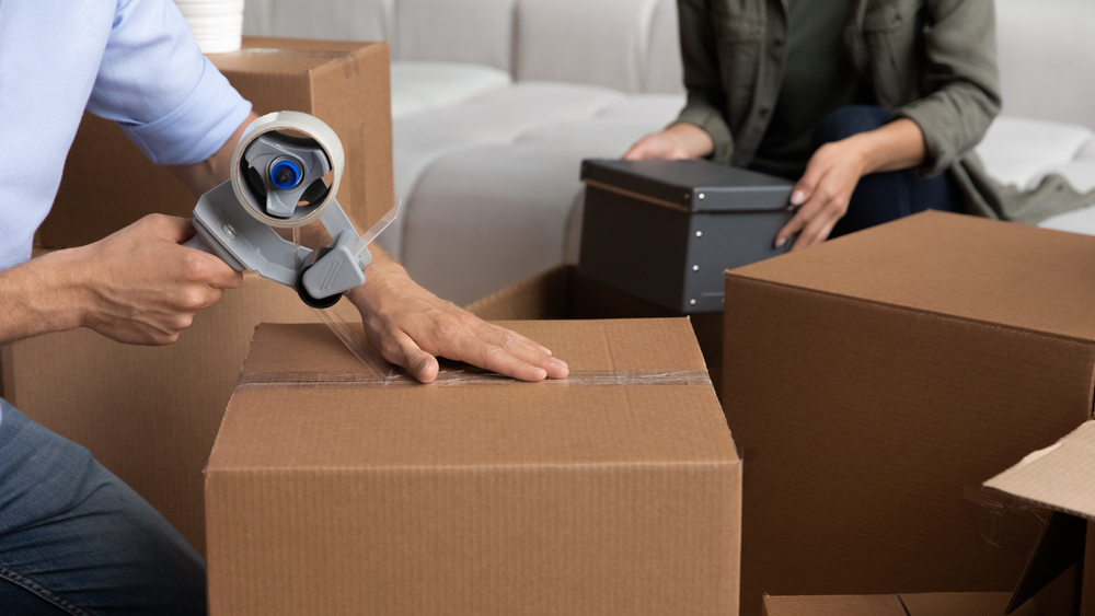 couple sealing moving boxes