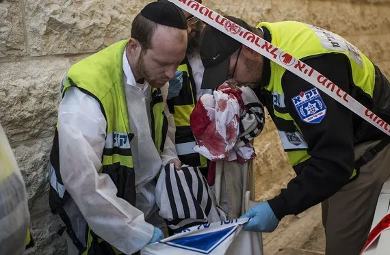 Emergency personnel holding a bloody prayer shawl