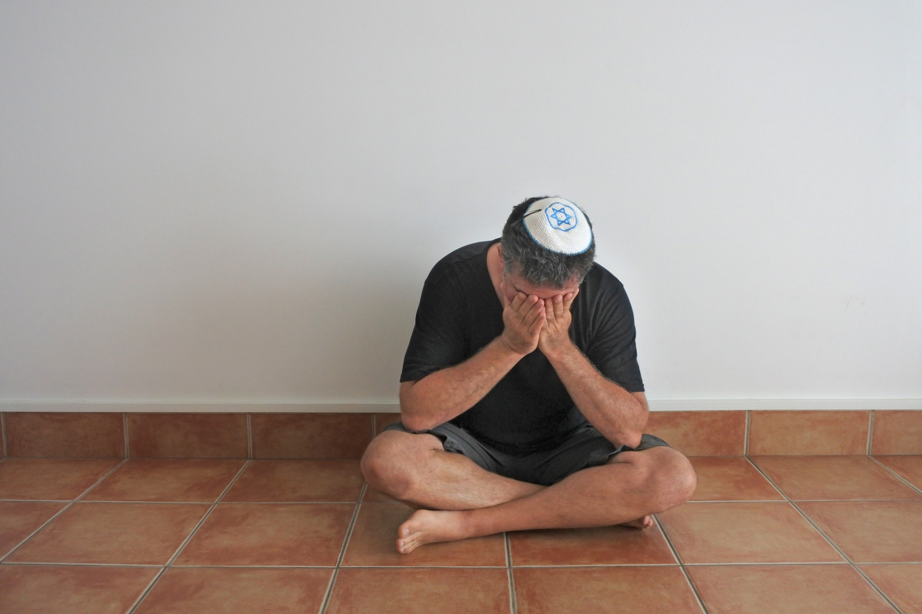 Jewish man sitting on floor mourning