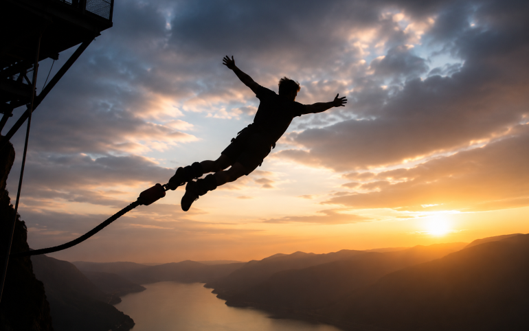Silhouette of a person bungee jumping above a mountain valley at sunset, illustrating the theme of living life like a dream.