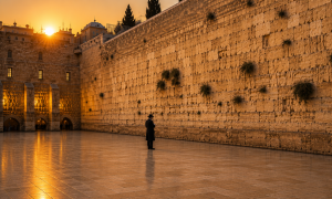 Person praying at the Kotel during the Three Weeks, expressing longing for the return of the Shechinah and greater K'vod Shamayim.